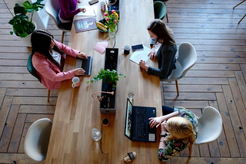 Overhead view of diverse women professionals working in a modern office setting, fostering collaboration and teamwork.