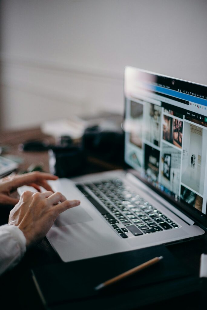 A person working on a laptop browsing visual content in an indoor setting, capturing digital creativity and remote work.